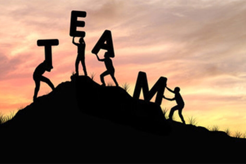 Working well with your team of spirit guides concept silhouette TEAM letters carried up mountain top by four persons